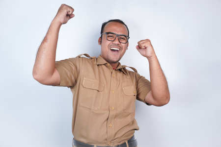 a man Asian civil servants or state civil servants is with brown uniform. gesture happy successful expression, raised a fist beside him On white background. Indonesia PNS, ASNの写真素材