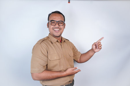 a man Asian civil servants or state civil servants is with brown uniform gesturing pointing at the copy space on above him On white background. Indonesia PNS, ASNの写真素材