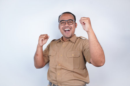 a man Asian civil servants or state civil servants is with brown uniform. gesture happy successful expression, raised a fist beside him On white background. Indonesia PNS, ASNの写真素材