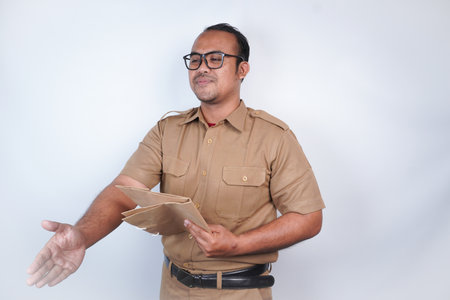 a man Asian civil servants or state civil servants is with brown uniform. gesturing shake hands and bring documents . On white background. Indonesia PNS, ASNの写真素材