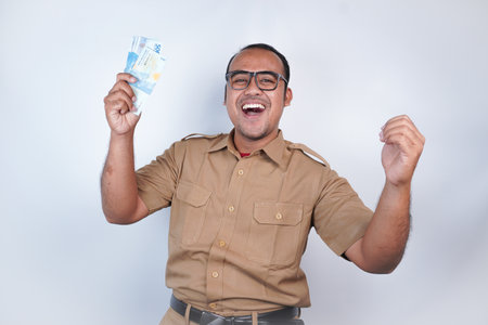 a man Asian civil servants or state civil servants is with brown uniform. gesturing happy to get money, get salary, receive taxes . On white background. Indonesia PNS, ASNの写真素材