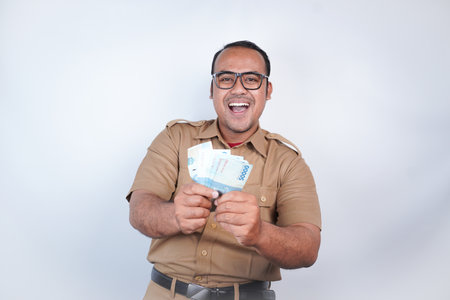a man Asian civil servants or state civil servants is with brown uniform. gesturing happy to get money, get salary, receive taxes . On white background. Indonesia PNS, ASNの写真素材