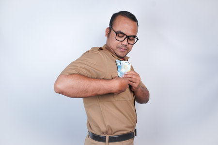 a man Asian civil servants or state civil servants is with brown uniform. gesturing take bribes. money. On white background. Indonesia PNS, ASNの写真素材