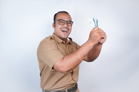 a man Asian civil servants or state civil servants is with brown uniform. gesturing happy to get money, get salary, receive taxes . On white background. Indonesia PNS, ASNの写真素材
