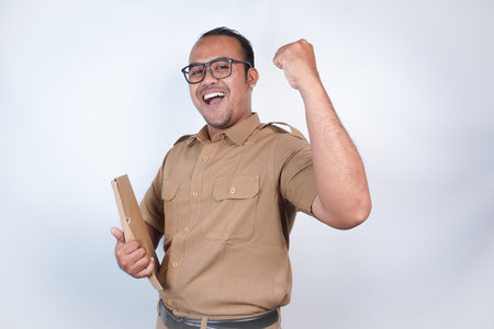 a man Asian civil servants or state civil servants is with brown uniform. gesture happy successful expression, raised a fist beside him On white background. Indonesia PNS, ASNの写真素材