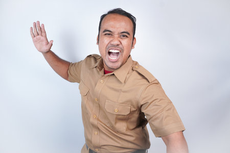 a man Asian civil servants or state civil servants is with brown uniform. gesturing angry will hit, slap. On white background. Indonesia PNS, ASNの写真素材
