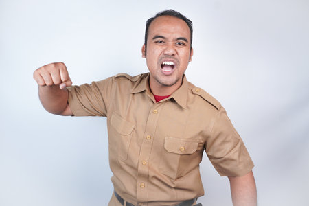 a man Asian civil servants or state civil servants is with brown uniform. gesturing angry will hit, slap. On white background. Indonesia PNS, ASNの写真素材