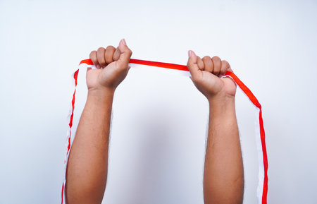 Hands clenched up showing ribbons with the red and white colors of the Indonesian flag