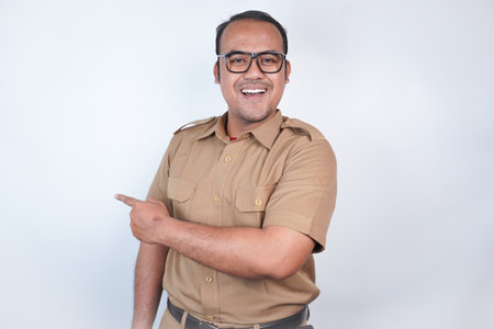 a man Asian civil servants or state civil servants is with brown uniform gesturing pointing at the copy space on beside him On white background. Indonesia PNS, ASNの写真素材