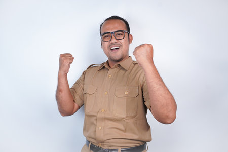 a man Asian civil servants or state civil servants is with brown uniform. gesture happy successful expression, raised a fist beside him On white background. Indonesia PNS, ASNの写真素材