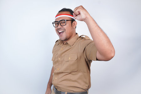 a man Asian civil servants or state civil servants is with brown uniform and red and white Headband gesture happy successful expression, raised a fist beside him On white background. Indonesia PNS, ASNの写真素材