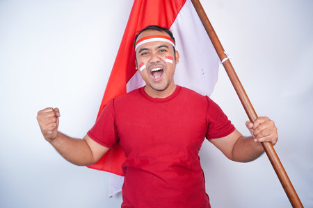 Indonesian men celebrate Indonesian independence day with spirit on 17 August by holding the Indonesian flag isolated on white backgroundの写真素材