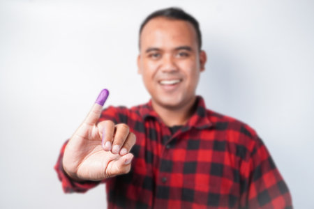 Young Asian man proudly showing her little finger dipped in purple ink after pemilu, or Indonesia election voting for president and parliamentary elections,の写真素材