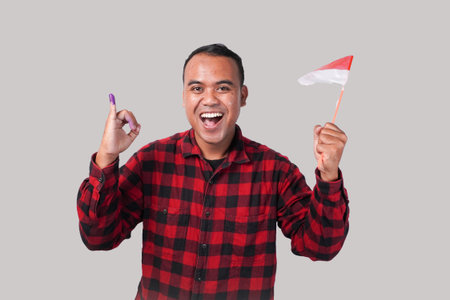 A man proudly displays the Indonesian flag and her little finger dipped in purple ink after the pemilu, or Indonesian election during the presidential and parliamentary election voting.の写真素材