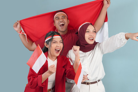 Indonesian supporters, Three Indonesian people are holding their country flag smiling and pointing...