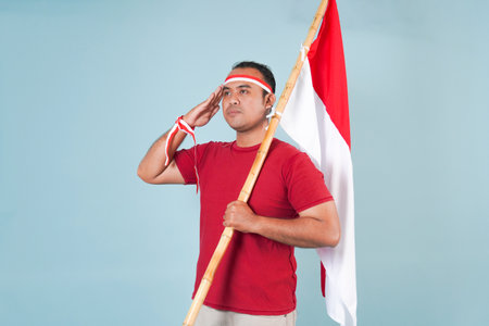 Energetic young Indonesian man holding a flag while posing respectfully, Indonesian Independence Day...