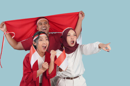 Indonesian supporters, Three Indonesian people are holding their country flag smiling and pointing...