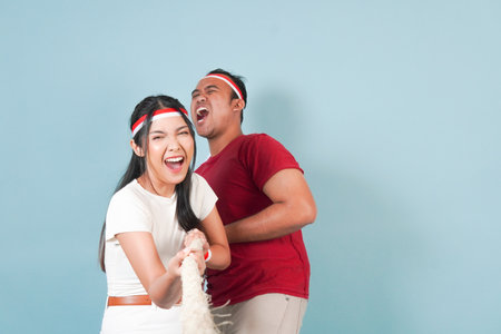 Two couple Indonesian wearing flag headband are pulling on a rope, joining competition for...