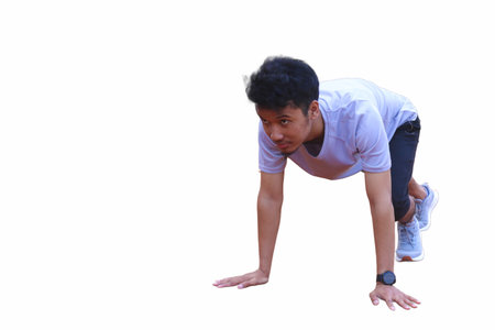 Young asian runner ready to running in the start position on dirt field. The man is wearing a grey shirt and black shorts isolated white backgroundの写真素材