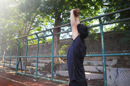 A man is stretching his arm in front of a fence. Concept of determination and focus as the man works...