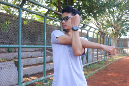 A man is stretching his arm in front of a fence. Concept of determination and focus as the man works...