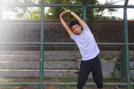 A man is stretching his arm in front of a fence. Concept of determination and focus as the man works...