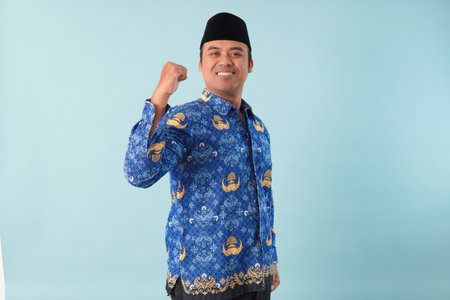 Indonesian government worker wearing kopri blue batik uniform He is raising hands in the air for a...