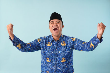 Excited Indonesian government worker wearing kopri blue batik uniform He is posing for a picture PNS, ASN civil servant concept.の写真素材
