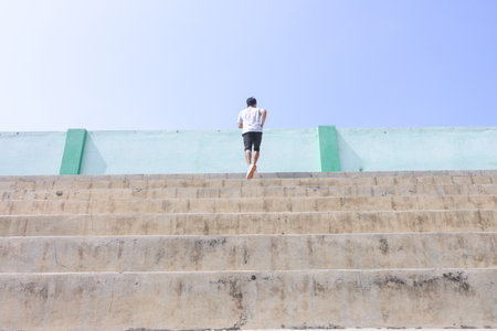 A man is running up a set of stairs. Concept of determination and perseverance as the man pushes...
