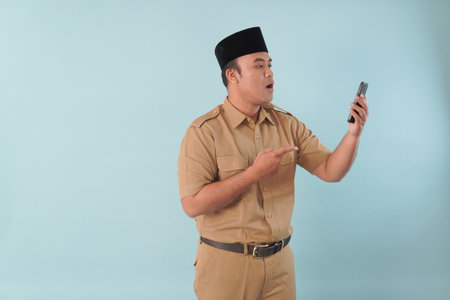 Smiling government worker with khaki uniform He is doing video call while pointing to his smartphone...