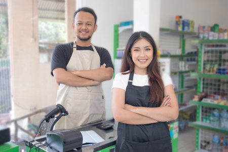 couple Friendly Asian cashier welcoming customer with open arms, cashier is wearing black and cream...
