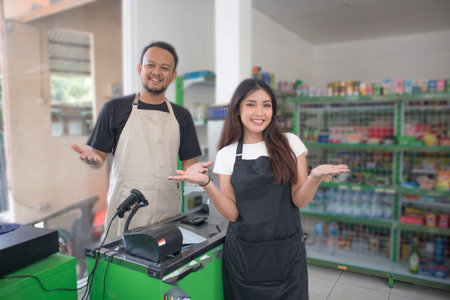 couple Friendly Asian cashier welcoming customer with open arms, cashier is wearing black and cream...