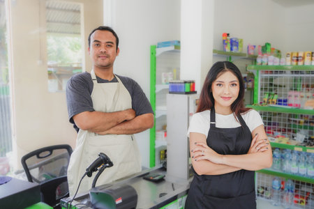 couple Friendly Asian cashier welcoming customer with open arms, cashier is wearing black and cream...