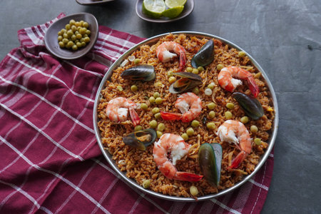 Paella is a Spanish dish made from rice, seafood, shrimp, clams, lemon, peas with saffron seasoning.