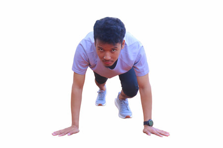 Young asian runner ready to running in the start position on dirt field. The man is wearing a grey...