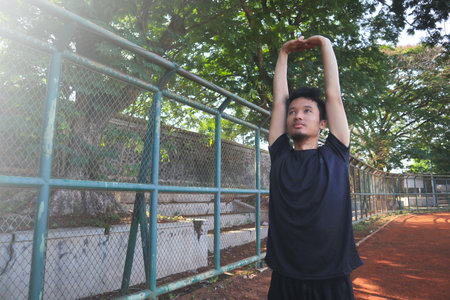 A man is stretching his arm in front of a fence. Concept of determination and focus as the man works...