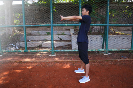 A man is stretching his arm in front of a fence. Concept of determination and focus as the man works...