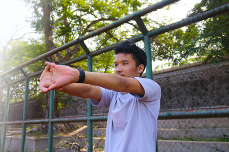 A man is stretching his arm in front of a fence. Concept of determination and focus as the man works...