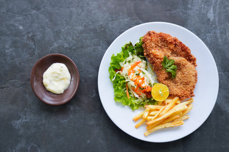 Chicken schnitzel is made from chicken breast, served with French fries, lemon, vegetable salad and...