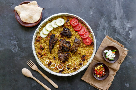 Traditional Kebuli Rice with Lamb, aromatic spiced rice dish cuisine, served with tender meat, raisins, cucumber, onion, seasoning and fresh tomato slicesの写真素材