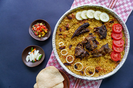 Traditional Kebuli Rice with Lamb, aromatic spiced rice dish cuisine, served with tender meat, raisins, cucumber, onion, seasoning and fresh tomato slicesの写真素材