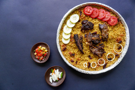 Traditional Kebuli Rice with Lamb, aromatic spiced rice dish cuisine, served with tender meat, raisins, cucumber, onion, seasoning and fresh tomato slicesの写真素材