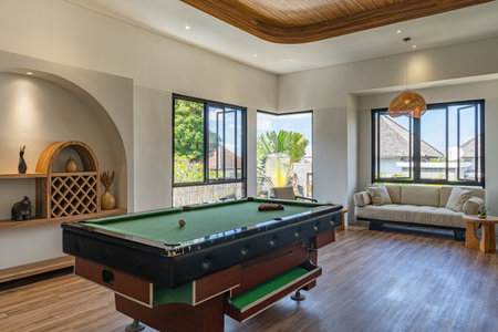 A pool table is surrounded by a room with a couch and a lamp. The room has a cozy