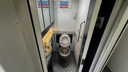 toilets on trains with a blue cover and a white lid. The toilet is in a small room