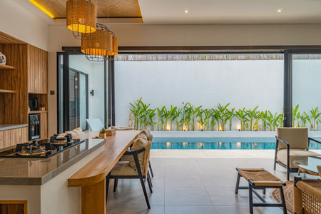 A large open living room with a kitchen and a pool. The kitchen has a stove and a sink. The living...