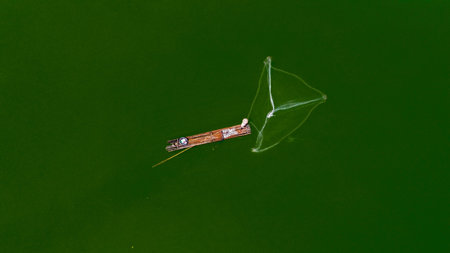 Aerial view of fishermen on bamboo rafts throwing and pulling fishing nets on lake