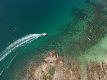Aerial view boat patrolling the island that have blue ocean and corals