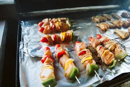 Skewers and Chicken drumsticks be places on aluminium foil for grill.