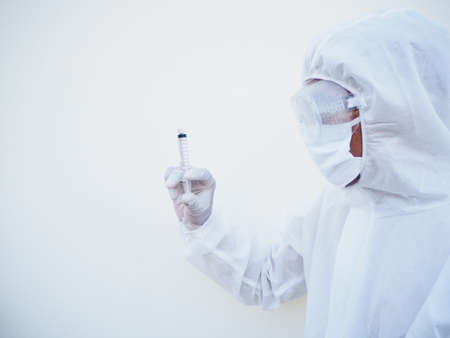 Asian doctor or scientist in PPE suite uniform holding medical injection syringe. coronavirus or...