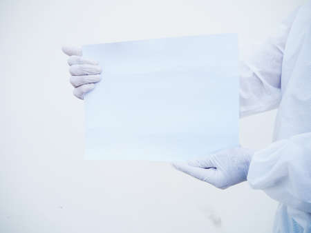 Closeup hands of doctor or scientist in PPE suite uniform holding blank paper for text with both hands While looking ahead. coronavirus or COVID-19 concept isolated white backgroundの写真素材